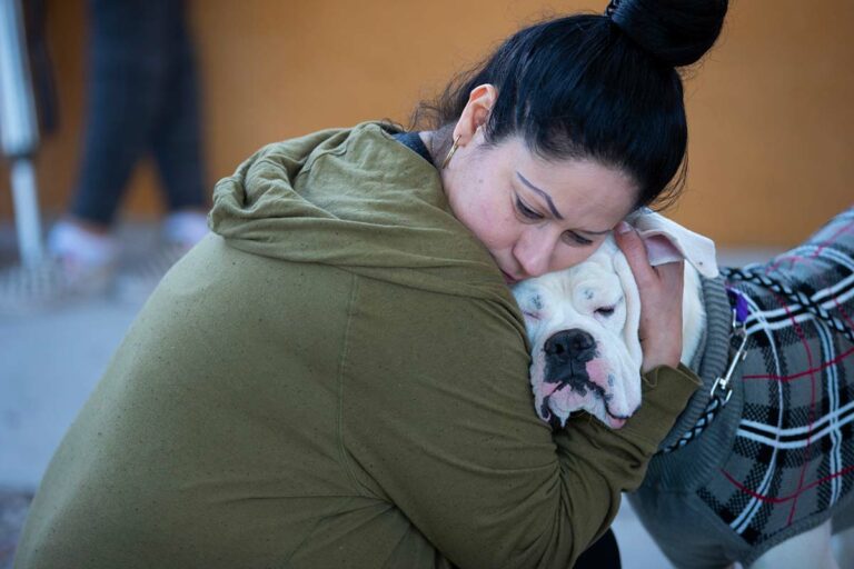 woman-in-green-hoodie-hugging-dog