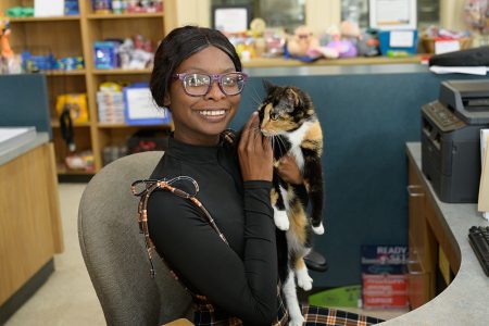 HASS Data and Research - woman petting a cat and sitting at a desk