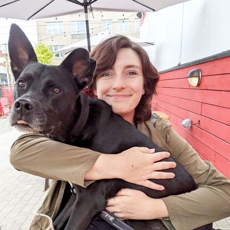 Eliza Torres hugging a black dog