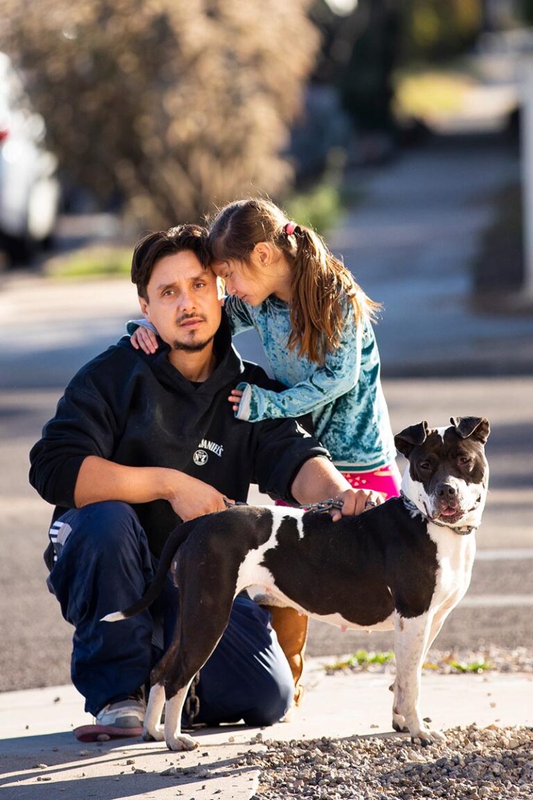 man with his daughter and black and white dog