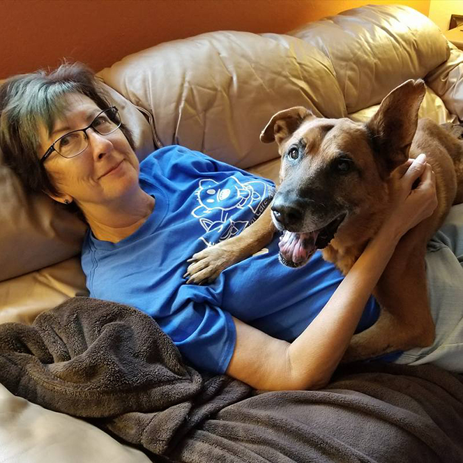 woman laying with foster dog on brown sofa